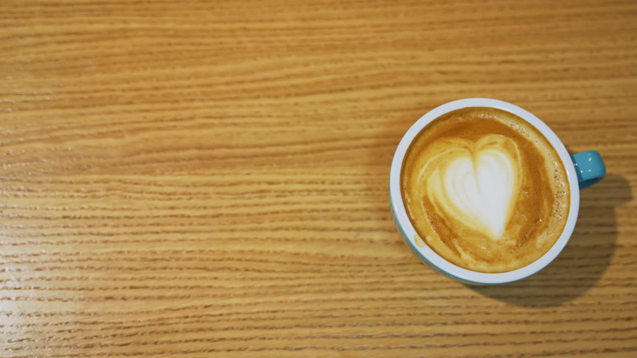 Cup of coffee close up. Coffee cup with art foam on wooden table
