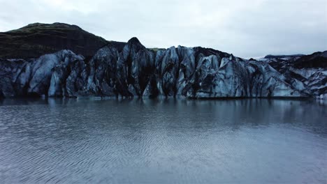 drone-flying-close-over-water-towards-Solheimajokull-glacier,-Iceland-4k