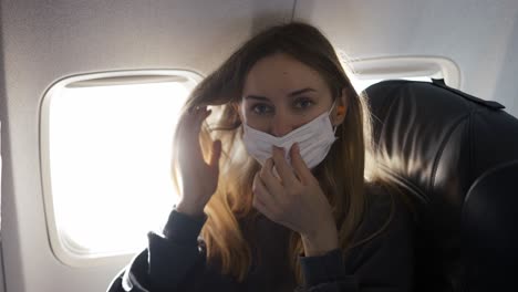 mujer rubia poniendo una máscara en el avión y sonriendo