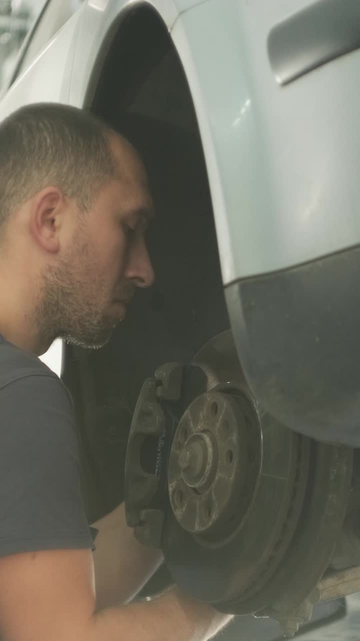 Mecánico trabajando en el sistema de frenos de un coche en un taller de reparación de automóviles.