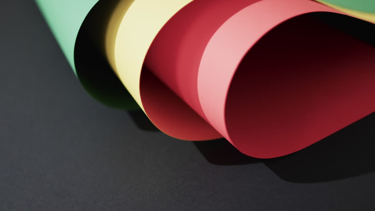 Video of rolled up red, yellow and green papers with copy space on black background