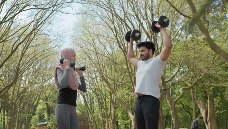 couple working out with dumbbells in a park