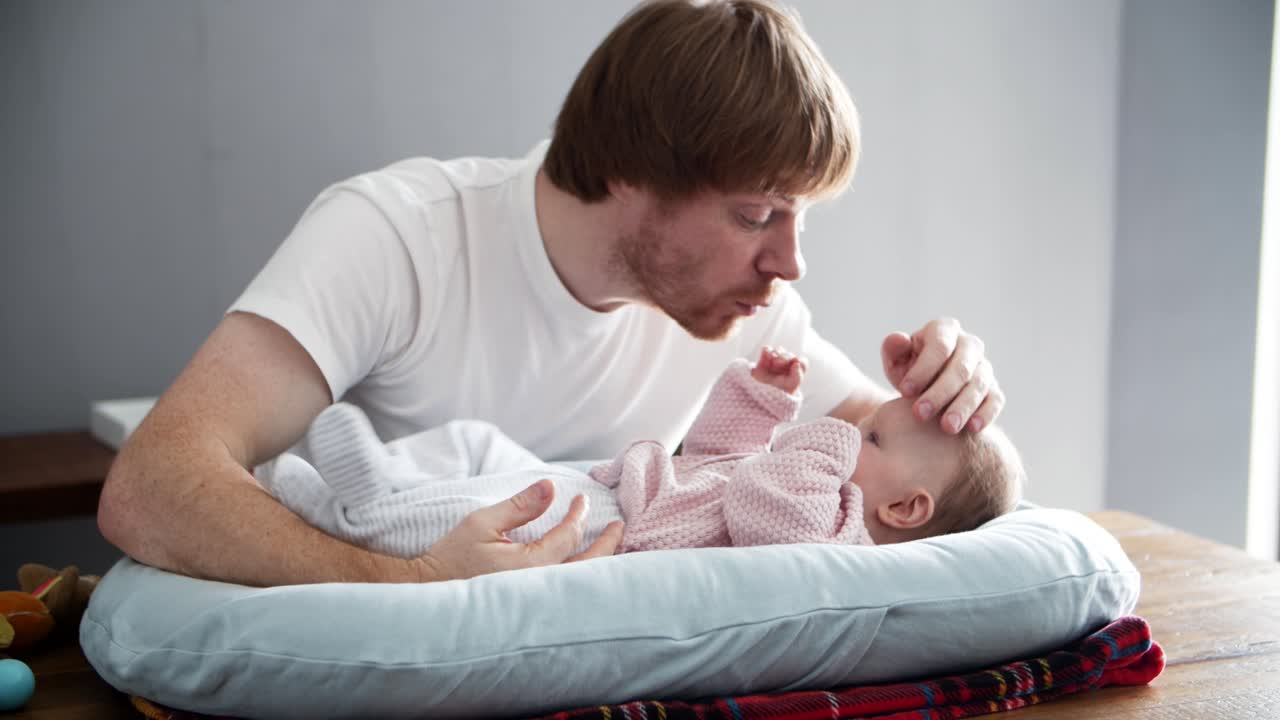 Careful dad laying baby daughter to sleep