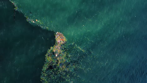 acqua blu dell'oceano ricoperta di isola dei rifiuti, vista aerea dall'alto verso il basso