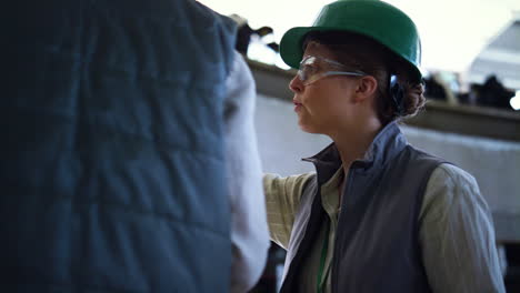 Livestock-worker-talking-colleague-at-milking-production-parlour-close-up.