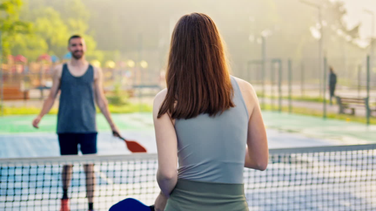 Man and woman doing a secret handshake after playing pickleball after rain