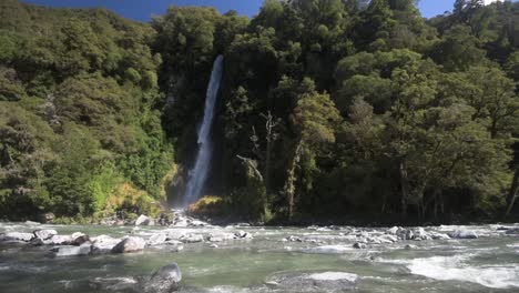 Gran-Angular-Que-Muestra-El-Río-Corriendo-Frente-A-Una-Cascada-En-Un-Denso-Bosque-Nativo