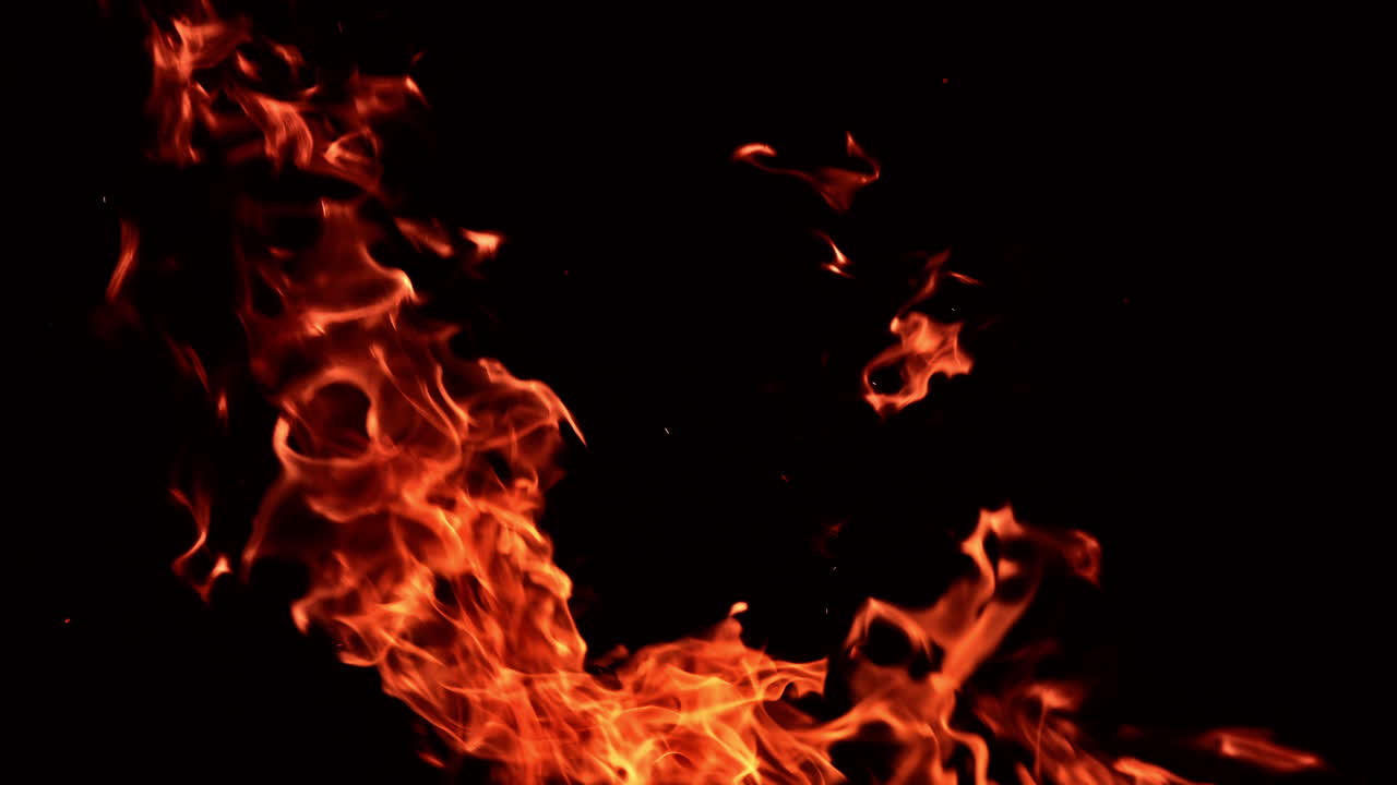 Raging fire flames dancing in the darkness. Orange flame rising and stretching up. Close up.
