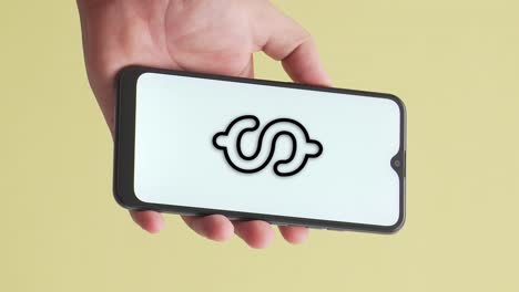 mano sosteniendo un teléfono en el que aparece la animación del símbolo del dólar en la pantalla