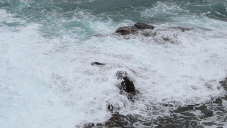 sea water during a tide crashing strongly into a stony shore full of obstacles and hitting rocks the water, then decomposes to a high incidence 4k slow motion capture at 60fps