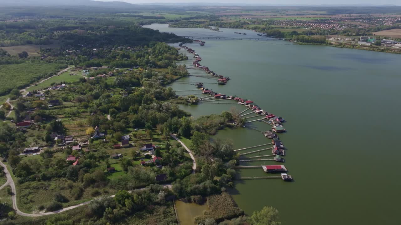 Flyfoto av hus på stylter over en rolig innsjø i Bokod, Ungarn