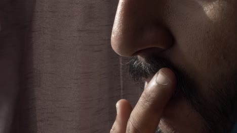 close up side view of adult male touch and stroking moustache with fingers