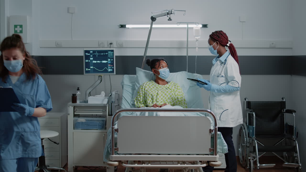 Medical specialist using tablet and talking to patient in bed