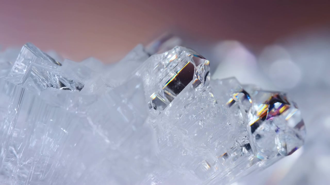 Una vista ravvicinata di cristalli di ghiaccio freschi e nitidi su uno sfondo rosato, che mostra la bellezza naturale e l'interesse scientifico delle formazioni ghiacciate in un ambiente freddo.