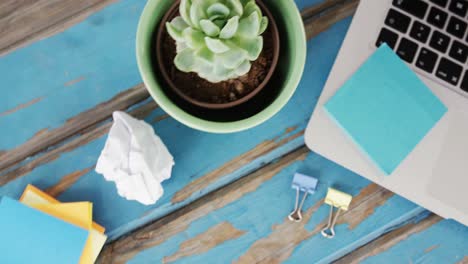 laptop, sticky notes, pot plant, pencil, crumpled paper and binder clips