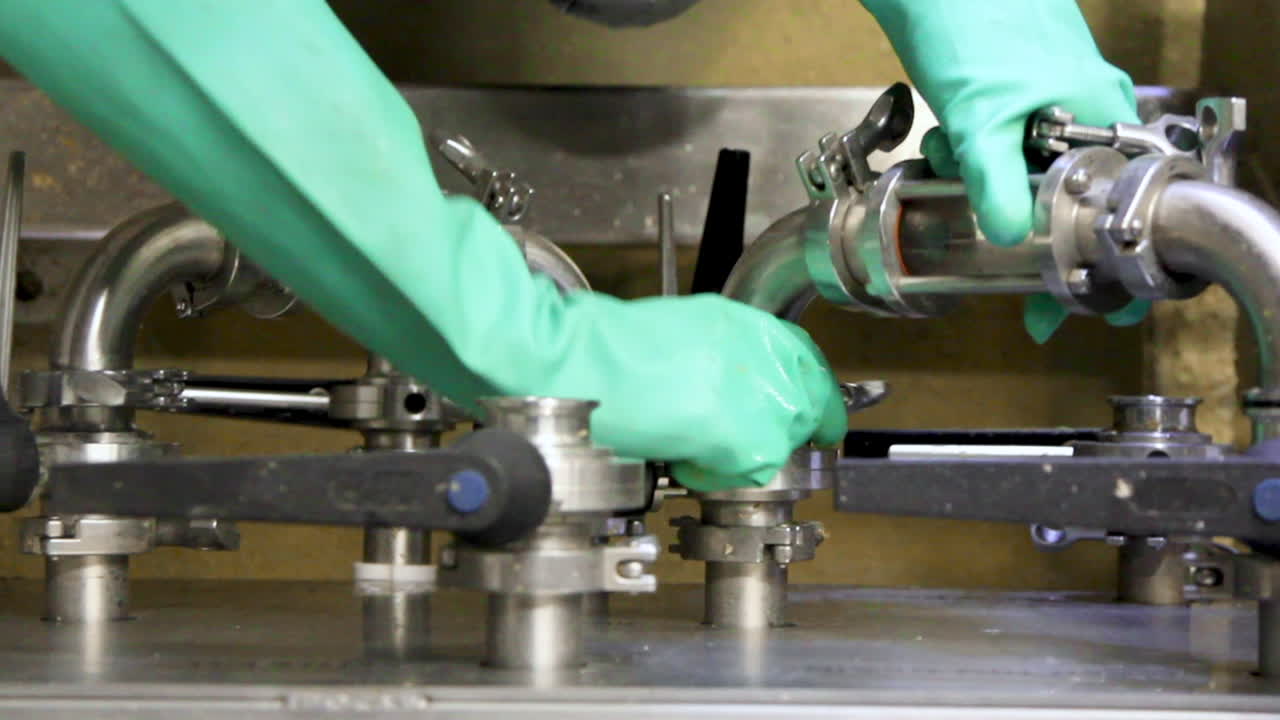 primer plano de un trabajador con guantes de protección que conecta el tubo para la producción de cerveza en la fábrica