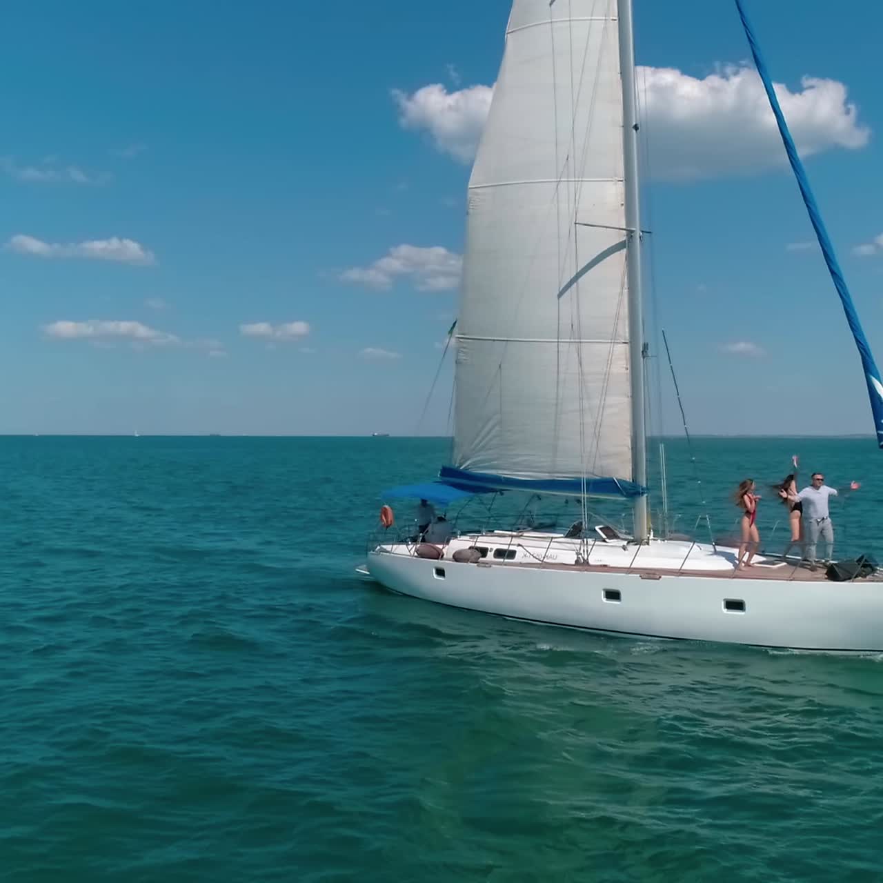 Luxury cruise on the open sea. White sailboat floating on blue water in a bright summer day. Young people resting on yacht. Musical group performing music on ship