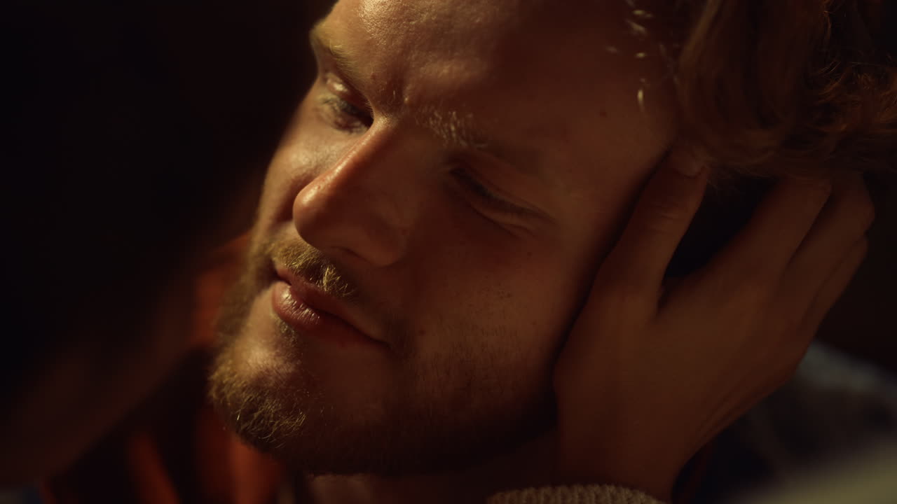 클로즈업 섹시한 남자친구는 저녁 불빛에서 부드럽게 보입니다. 데이트에서 손으로 얼굴을 만져요.