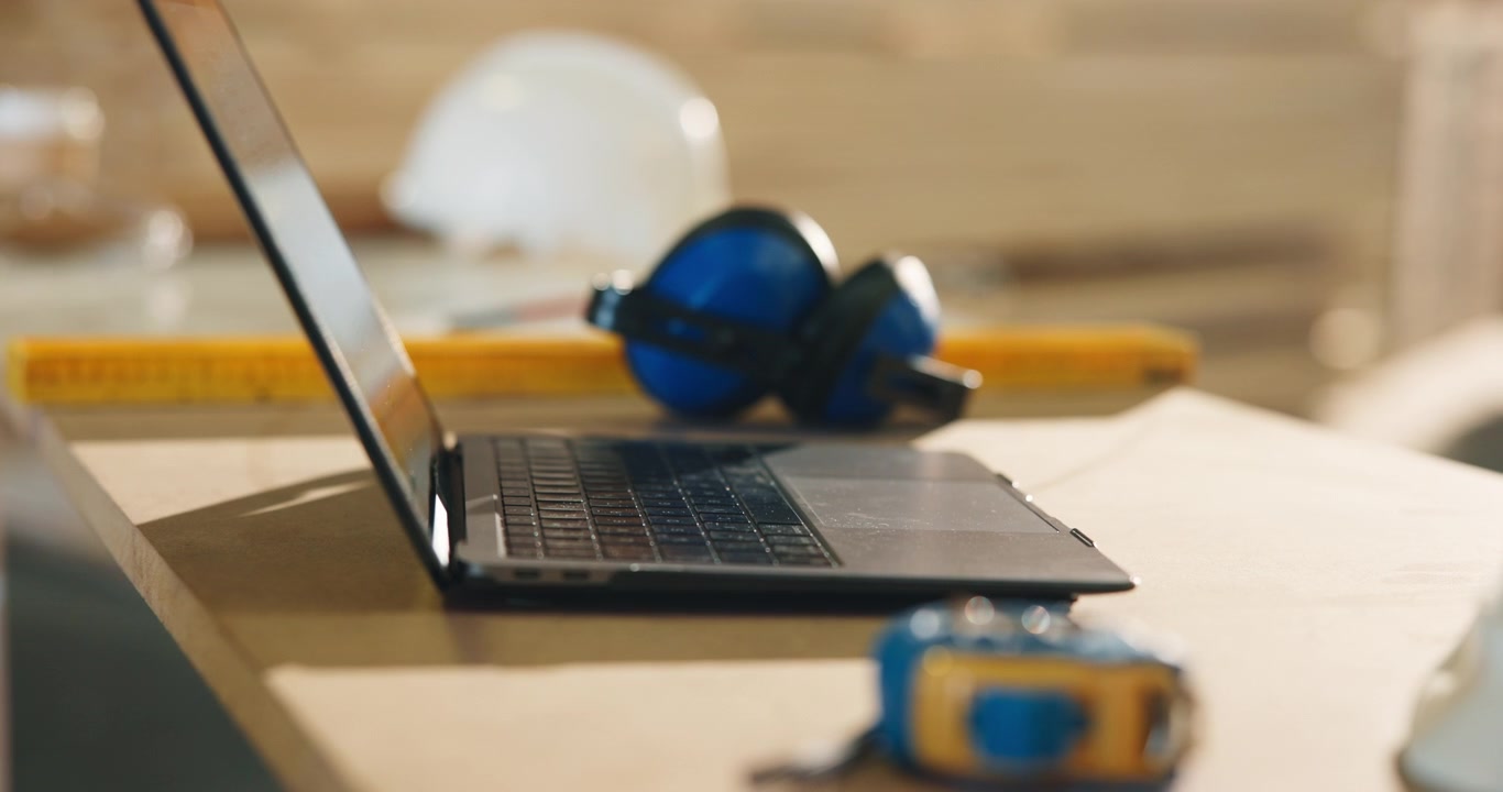 Laptop and Construction Tools on Workbench in Workshop