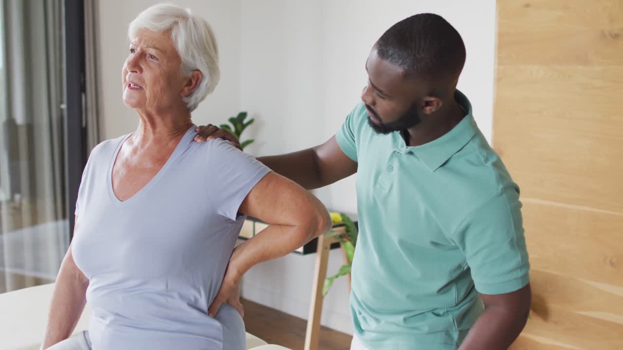 Video of caucasian senior woman practicing with african american male physiotherapist
