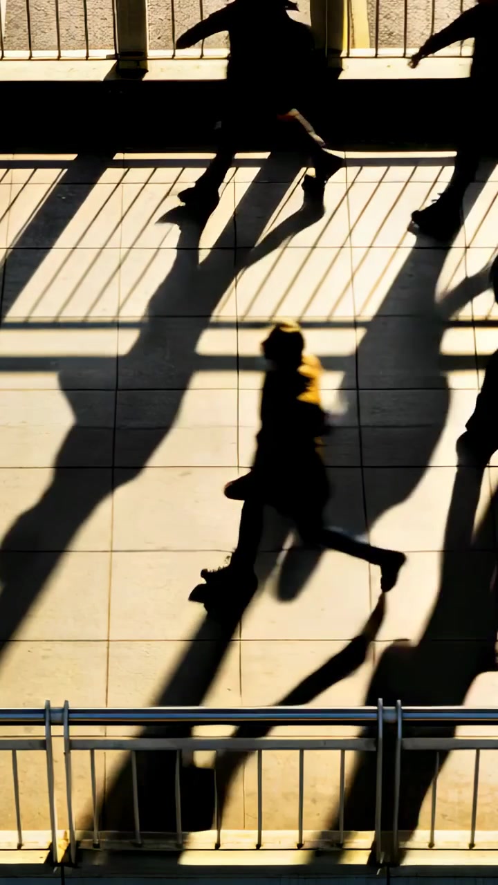 Vertical video: Entering group crossing walkway in shadow, yellow coat walking past rail en route