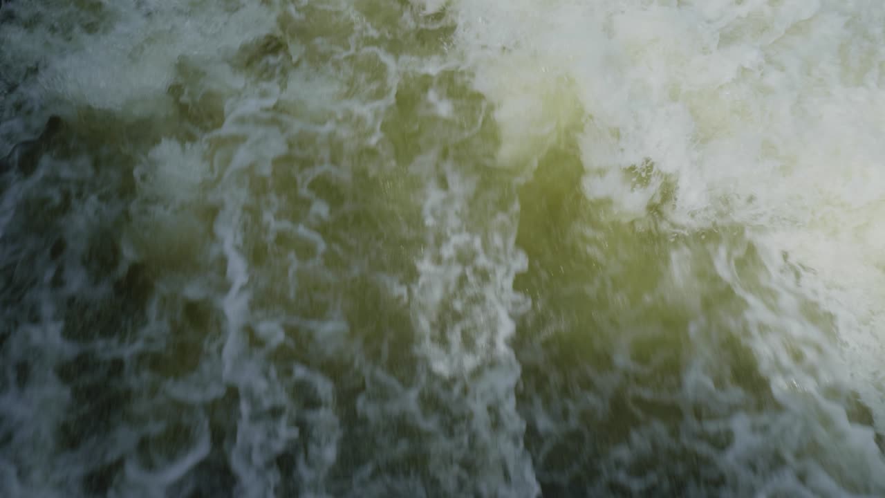 la inclinación del agua que entra en el río con bancos cubiertos de hierba y árboles de sauce