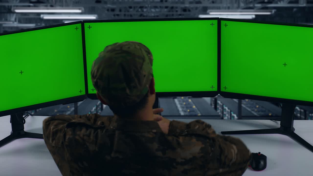 vista trasera de los militares asiáticos cansados estirándose mientras trabajaban con monitores de computadoras múltiples en el centro de datos