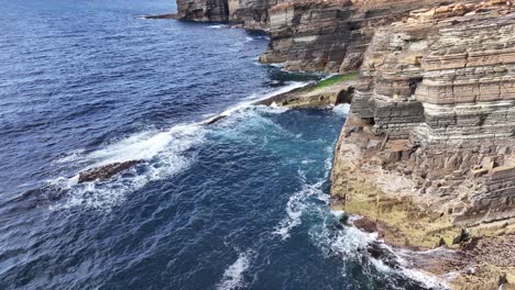 Aerial-View-of-Sunny-Coastline-of-Scotland-UK,-Steep-Cliffs-Above-Sea-Waves,-Drone-Shot-60fps