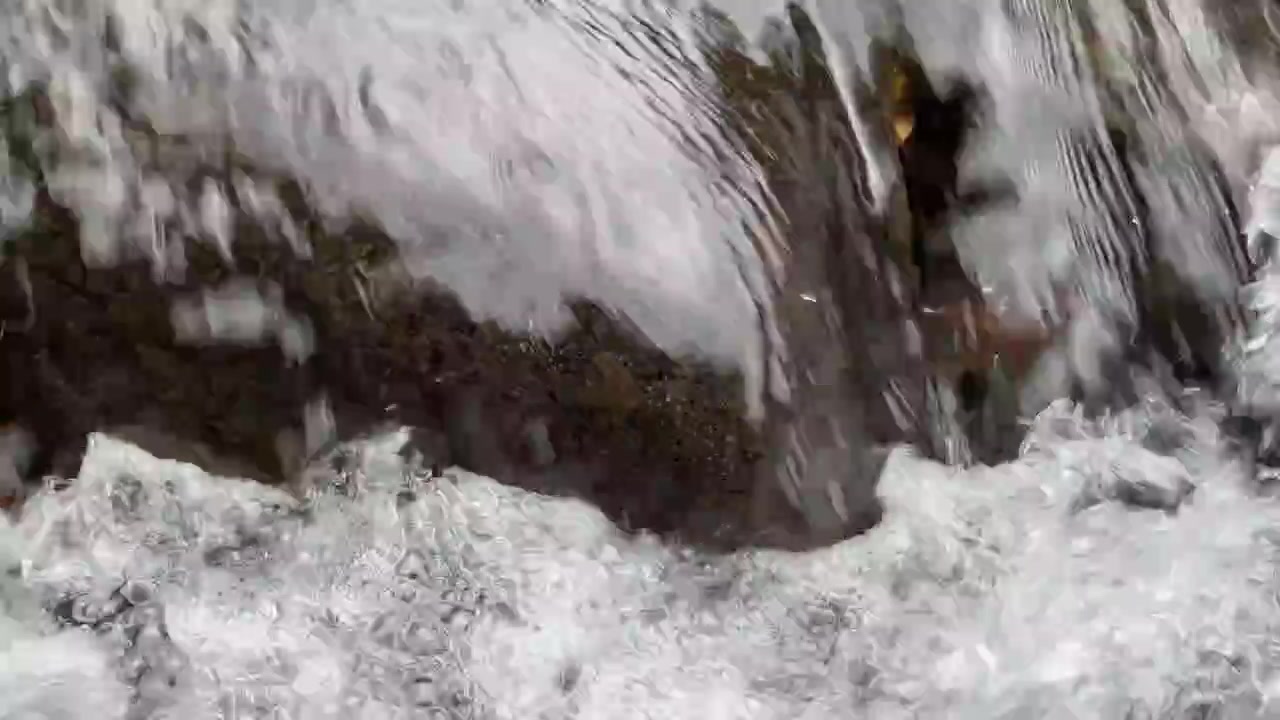 Acqua cristallina che scorre su rocce scure in un ruscello