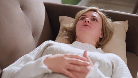 patient lying faced up on therapeutic chair hands resting on chest speaking about feelings in calm supportive environment with soft lighting warm tones conveying introspection vulnerability