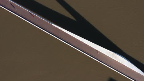 aerial shot of a sleek bridge, puente de la mujer, casting long shadows on the water, a minimalist urban scene