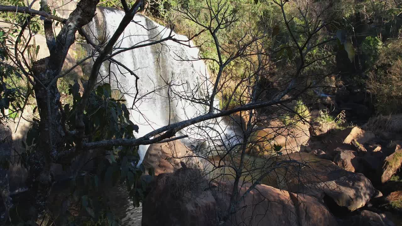 toma panorámica aérea de abajo hacia arriba de la hermosa cascada que se revela lentamente detrás de los árboles