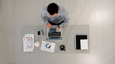 top view of businessman using a digital touch screen tablet and working at office desk