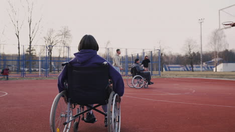 Behinderte-Frau-Im-Rollstuhl-Gibt-Ihren-Freunden-Auf-Dem-Basketballplatz-Ein-High-Five