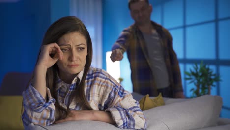mujer infeliz llorando, teniendo problemas en su matrimonio, en el fondo su marido está molesto.