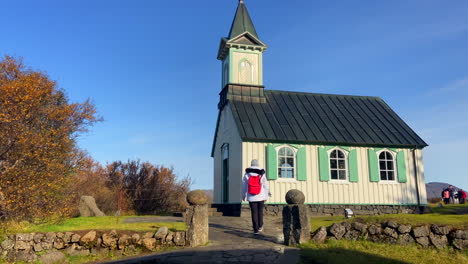 Female-tourist-approaching-Icelandic-fairytale-church-in-Thingvellir-at-sunny-day