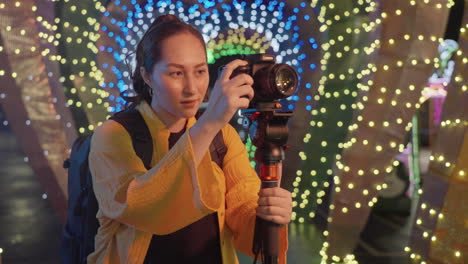 female photographer capturing pictures at night with camera mounted on a tripod