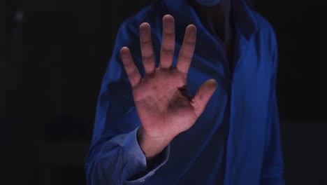 midsection of caucasian man in dark room using virtual digital interface with hand outstretched