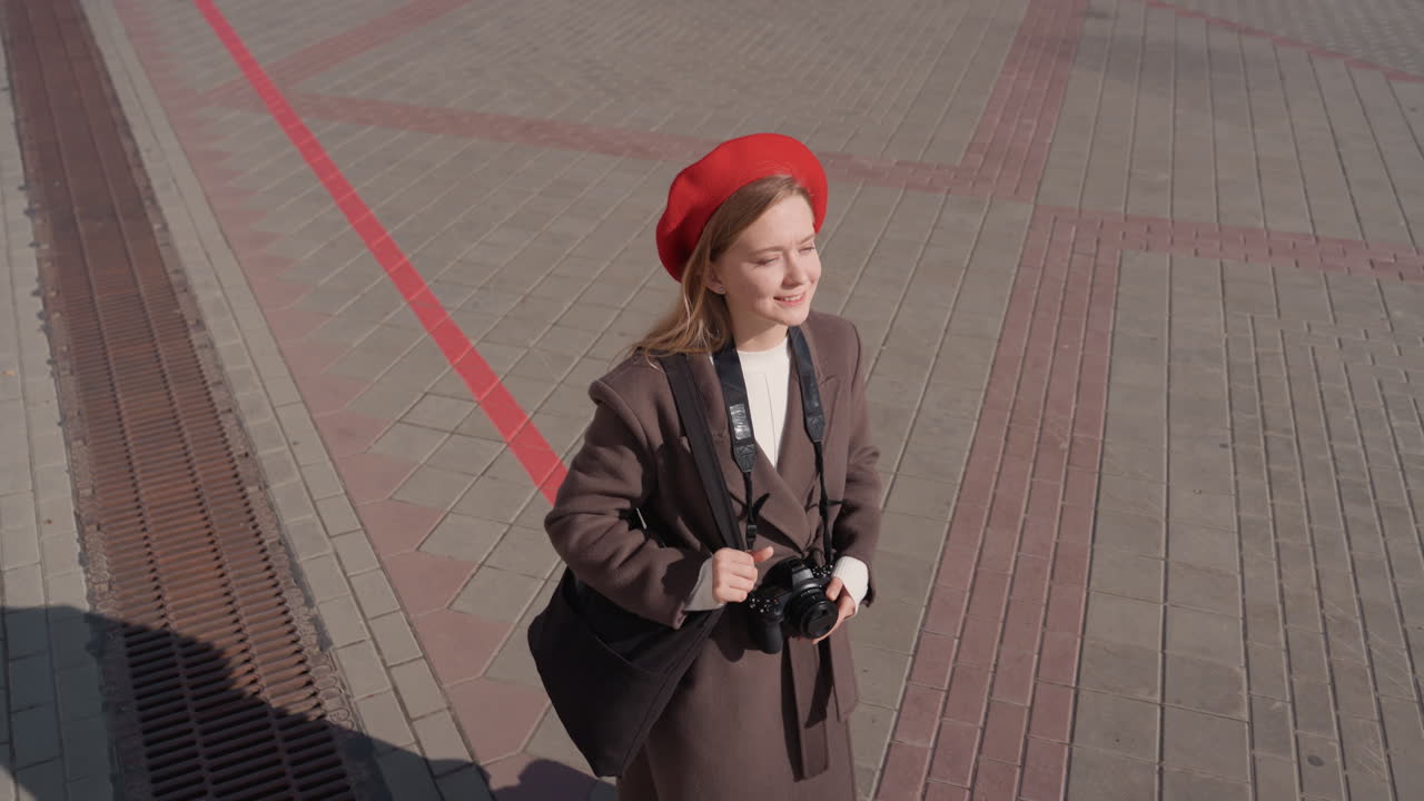 Kvindelig byudforskning. Kvinde går gennem torvet på en solrig dag. Kvinde i vintage-tøj nyder solrig byscene. Elegant kvinde i klassisk påklædning udforsker et livligt bycentrum i solskin.