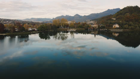 drone flies over the teal waters of lake caldonazzo towards sailboats