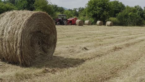 slide shot reveals farm machinery in field with golden bales of hay