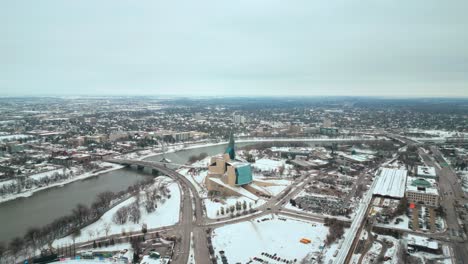 establishing shot canadian museum of human rights urban winnipeg manitoba canada downtown skyscraper buildings in city overcast landscape skyline snowing winter drone 4k shot spinning orbit