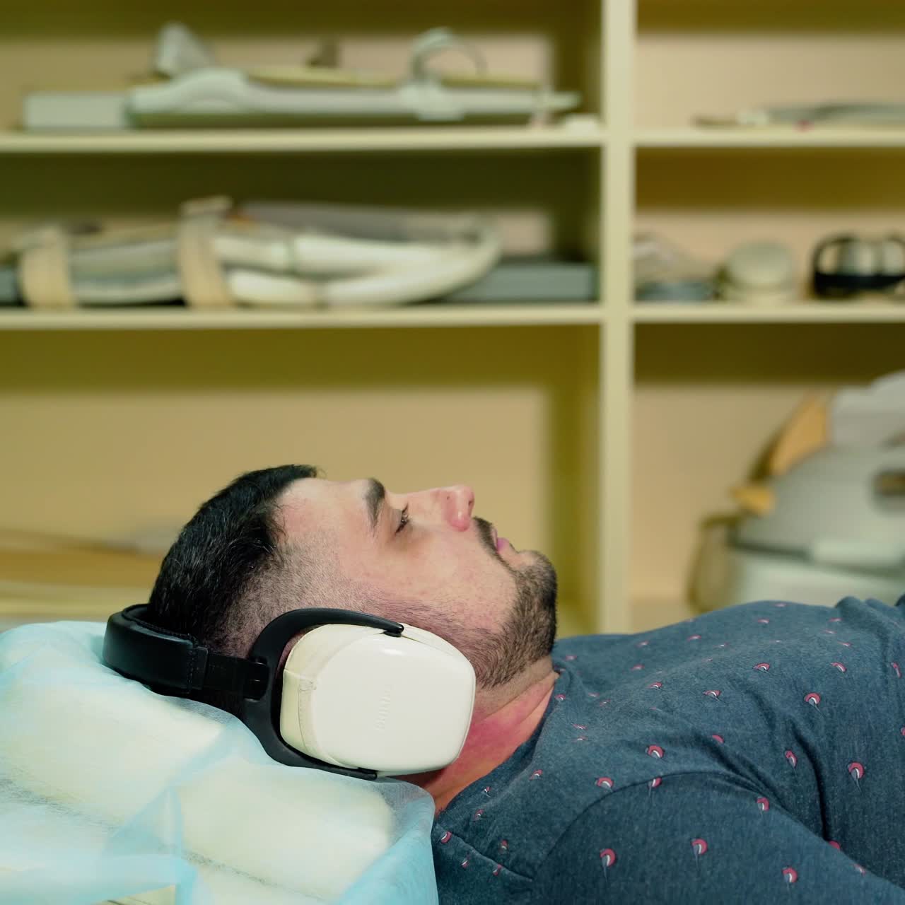 Patient and female laboratory radiologist in modern clinic. Male patient is lying in magnetic resonance image machine. Advanced MRI device in hospital.