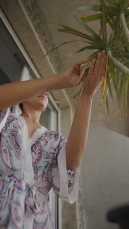 woman cleaning a plant on a balcony