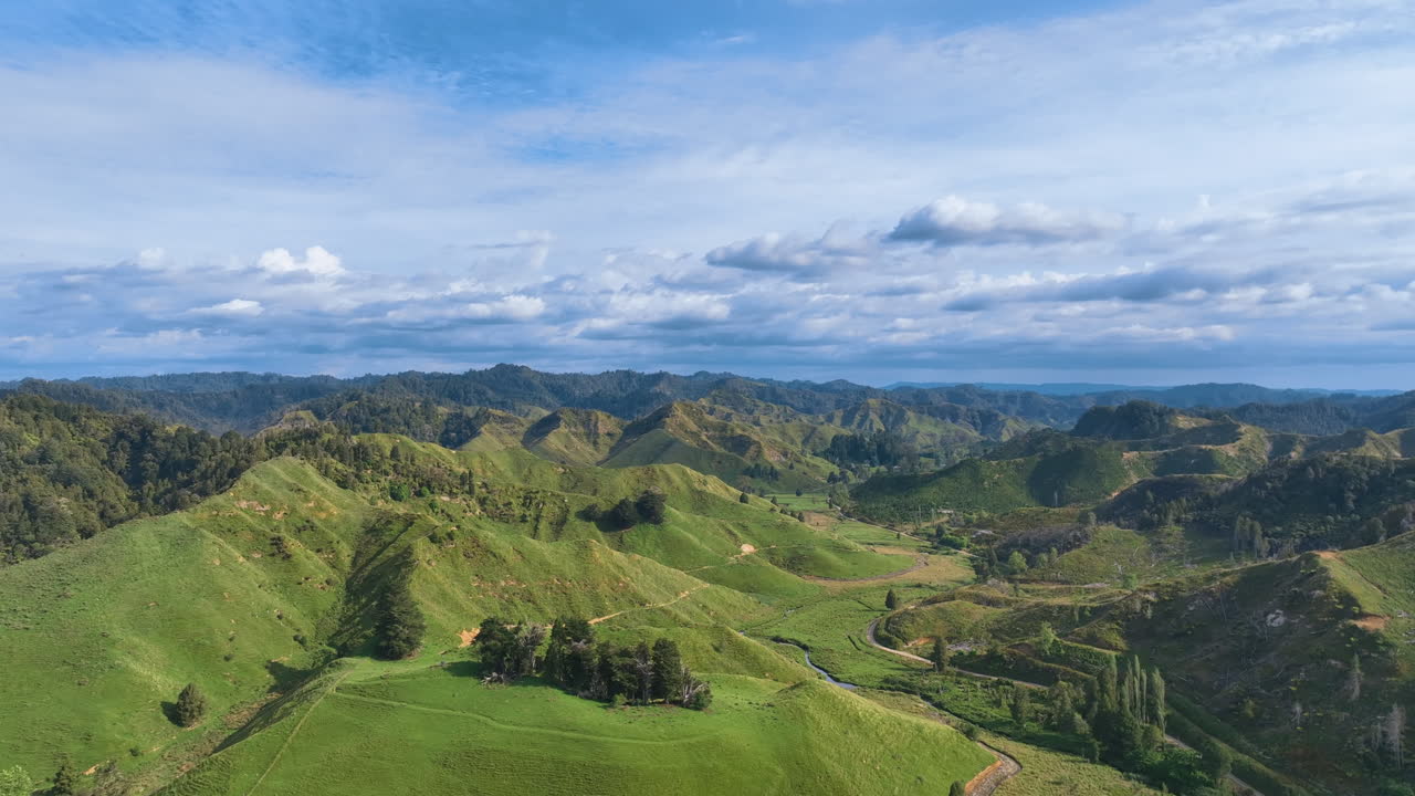 Aerial flies above New Zealand's famous Forgotten World highway connecting Taranaki with the King Country. A vast expanse of steep hills, lush green pastures, and recovering native forest