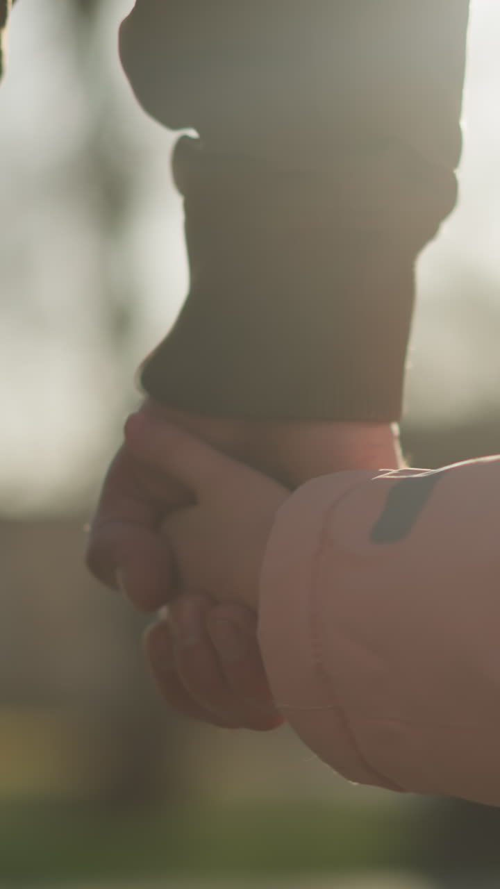 분홍색 재을 입은 작은 소녀가 갈색 재를 입은 남자와 손을 잡고, 모두 파란 청바지를 입고 함께 고 있는 클로즈업 뒷면