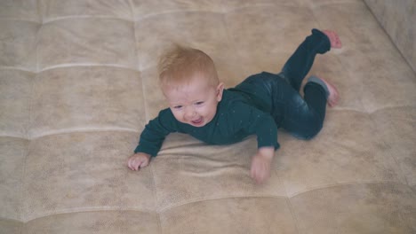 funny boy in jeans rests on large soft bed in children room