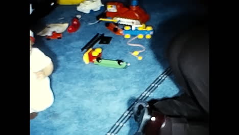 Young Boy Engaged in Playing With Toy Train Set. CIRCA USA - 1970s: A young boy in the 1970s USA is actively engaged in playing with a toy train set.