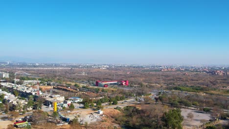 beautiful view of islamabad during the daytime as a drone flies away from the srinagar highway with traffic and residential buildings