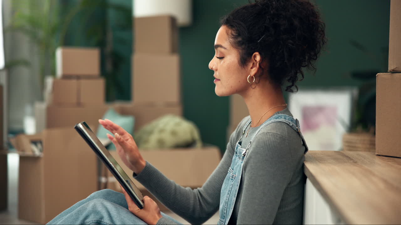 Woman using tablet surrounded by moving boxes